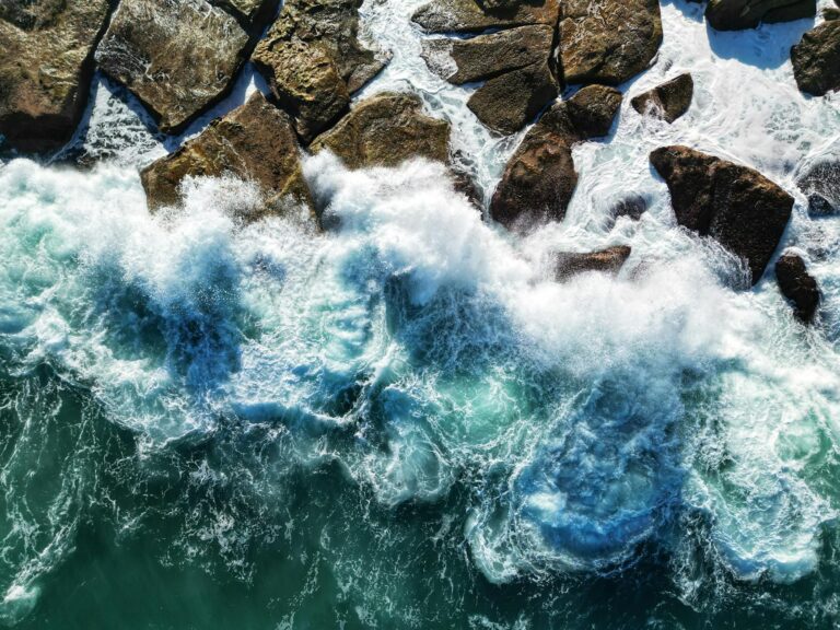 aerial view of ocean waves crashing on rocks
