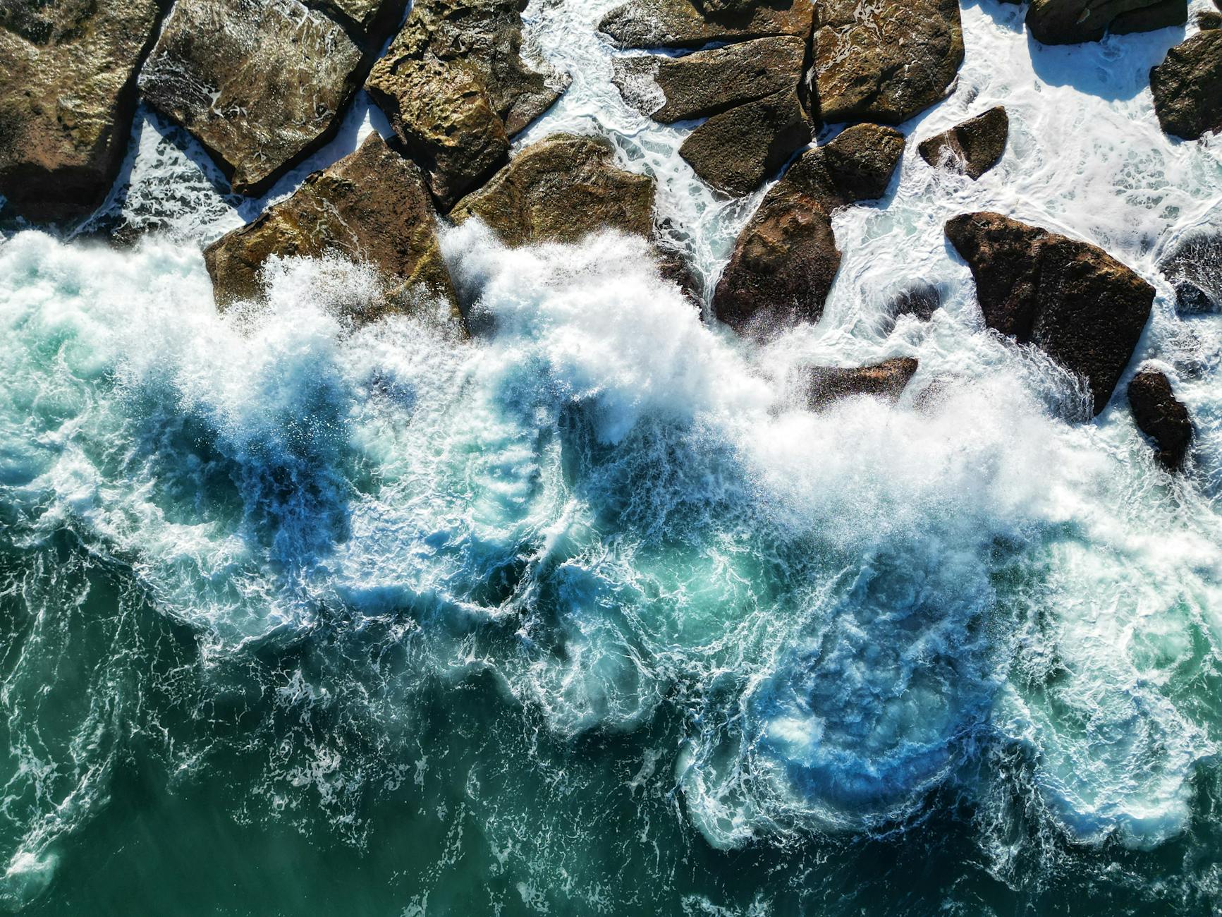 aerial view of ocean waves crashing on rocks